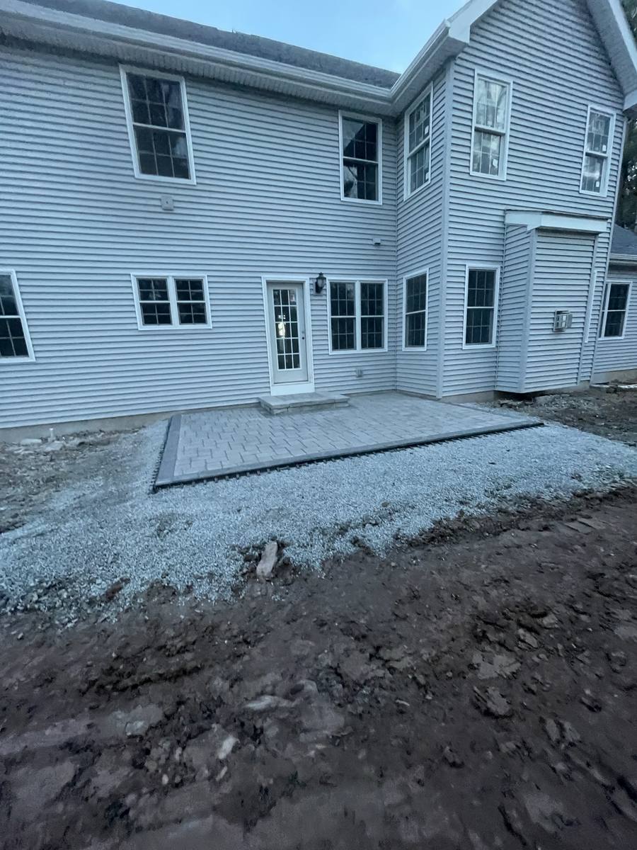 New paver patio with entry steps installed behind a two-story home