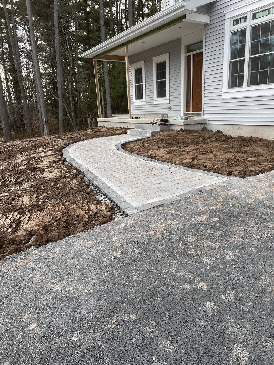 Curved paver walkway connecting the driveway to the covered front porch of a two-story home