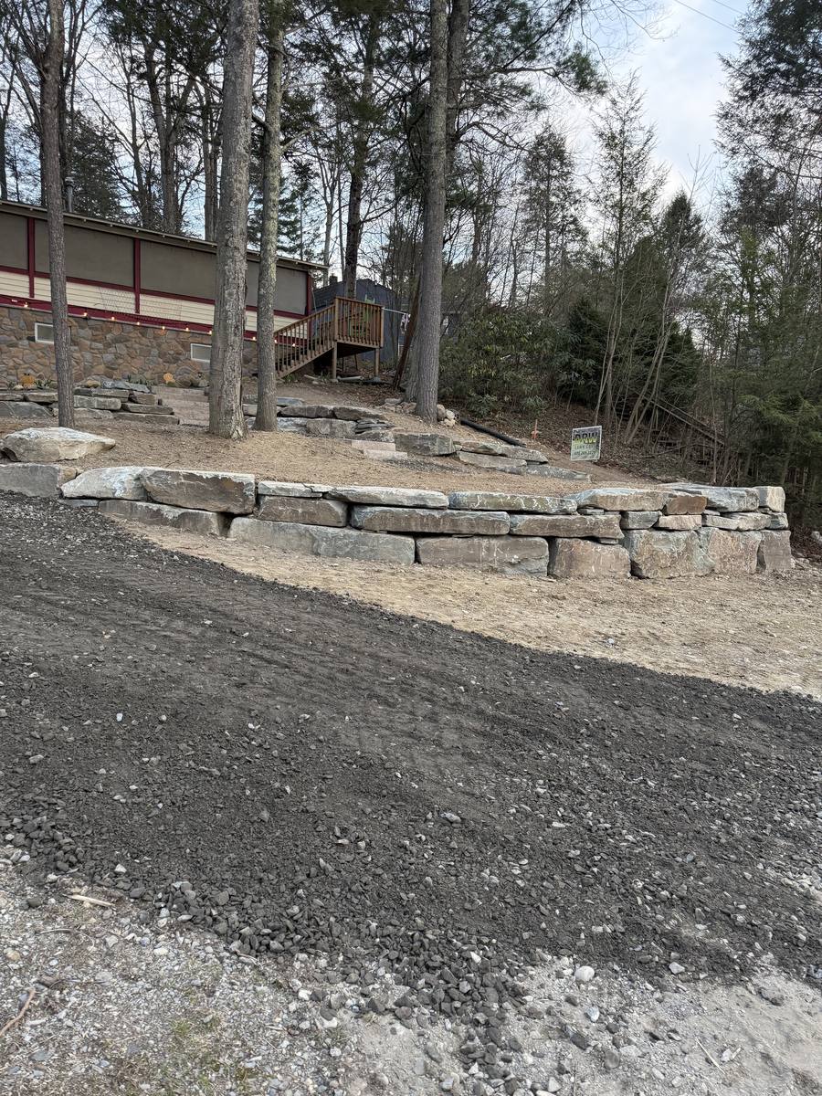 Unfinished stacked boulder retaining wall before capstones and steps were added