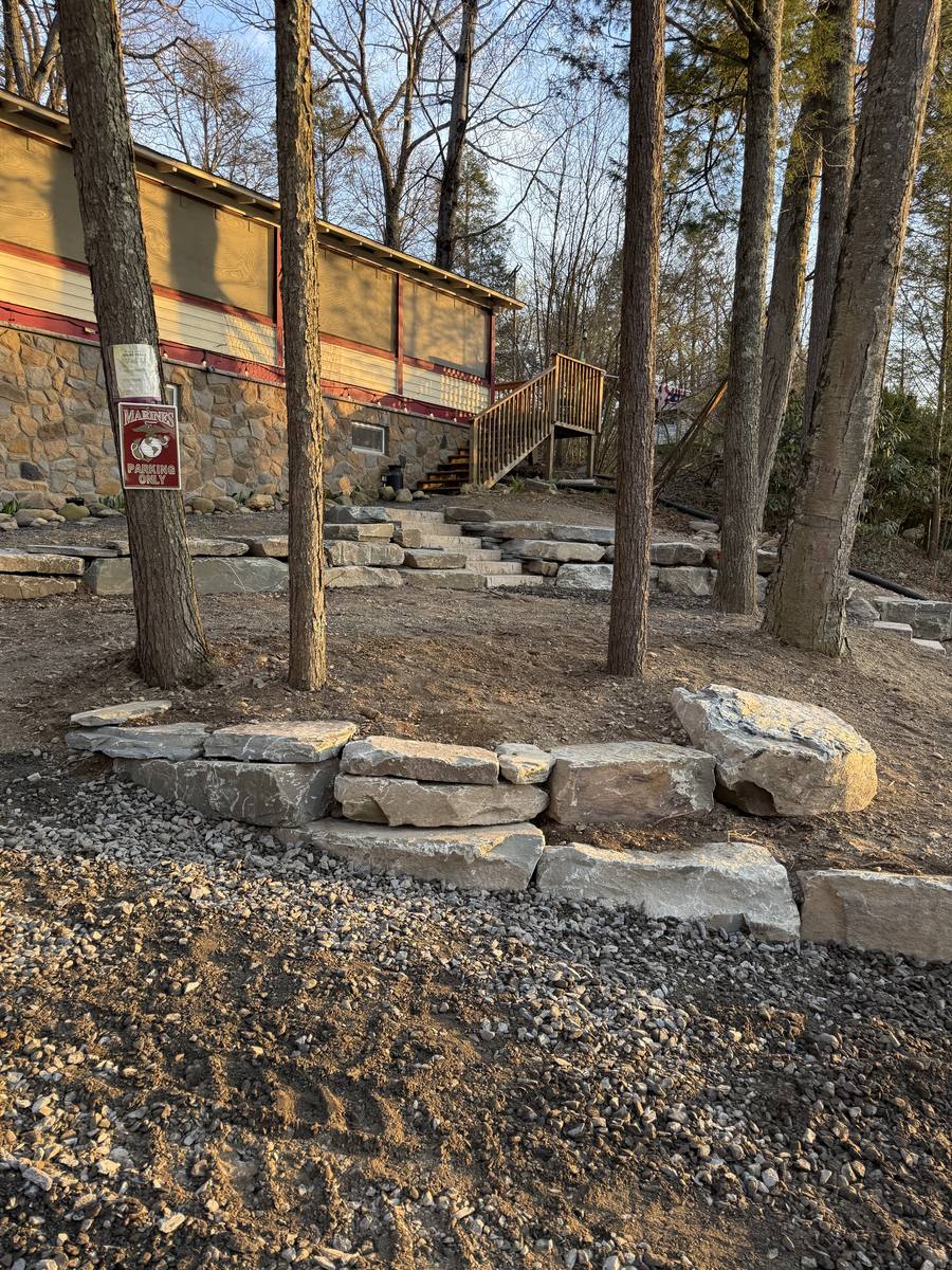 Natural stone retaining wall and matching stone steps set among tall pines at golden hour