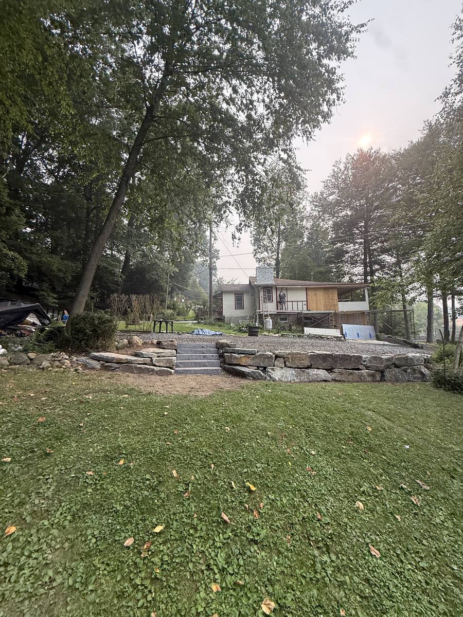 Stone retaining wall and steps leading up to a backyard patio area